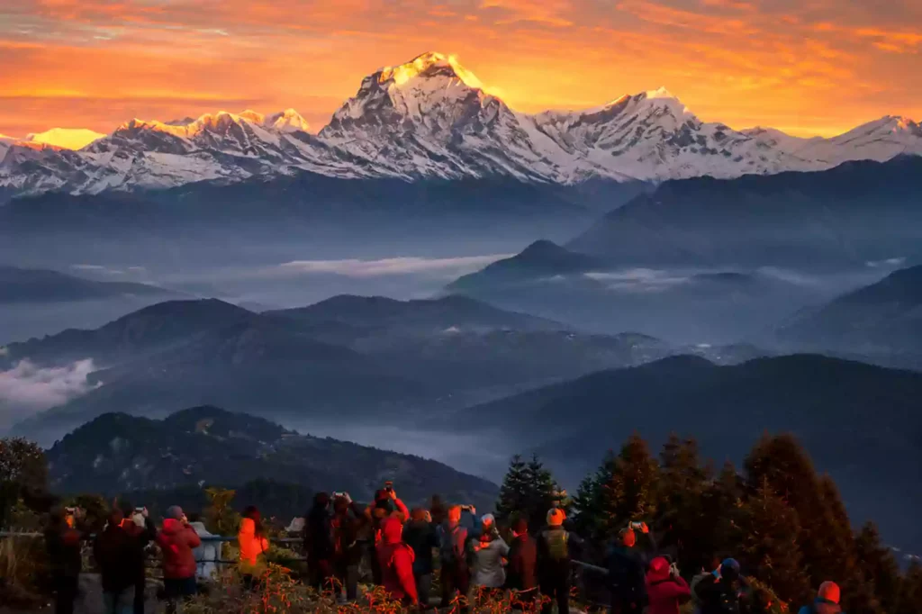 Trekkers at Annapurna Base Camp surrounded by towering snow-capped Annapurna peaks under clear alpine skies in Nepal.