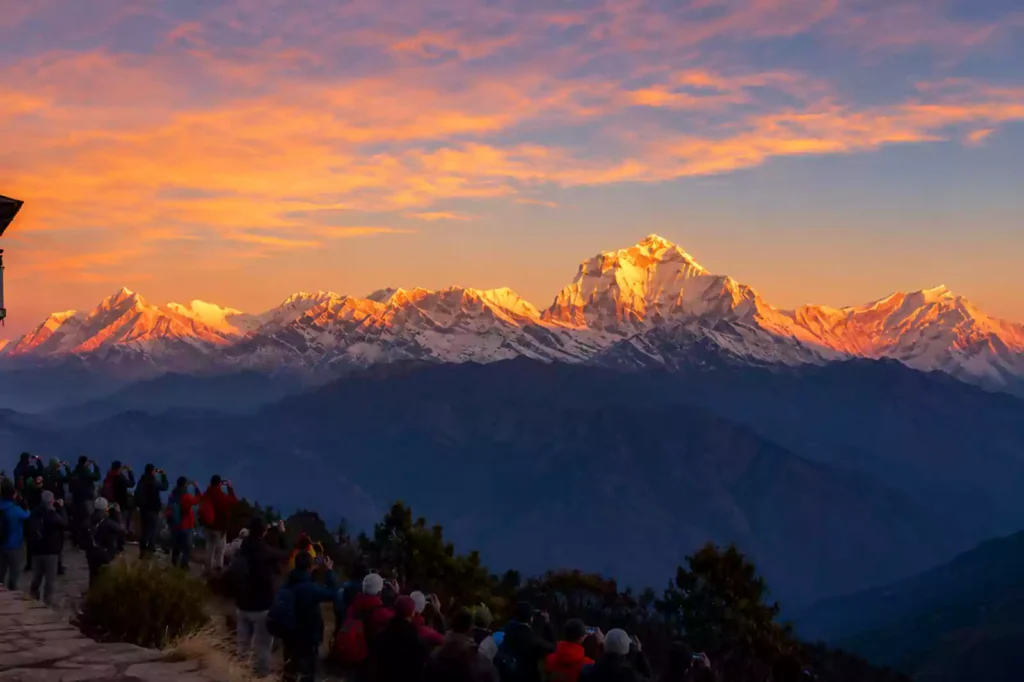 Sunrise panorama from Poon Hill viewpoint (3,210 m) overlooking the Annapurna and Dhaulagiri mountain ranges with trekkers enjoying the Himalayan sunrise.