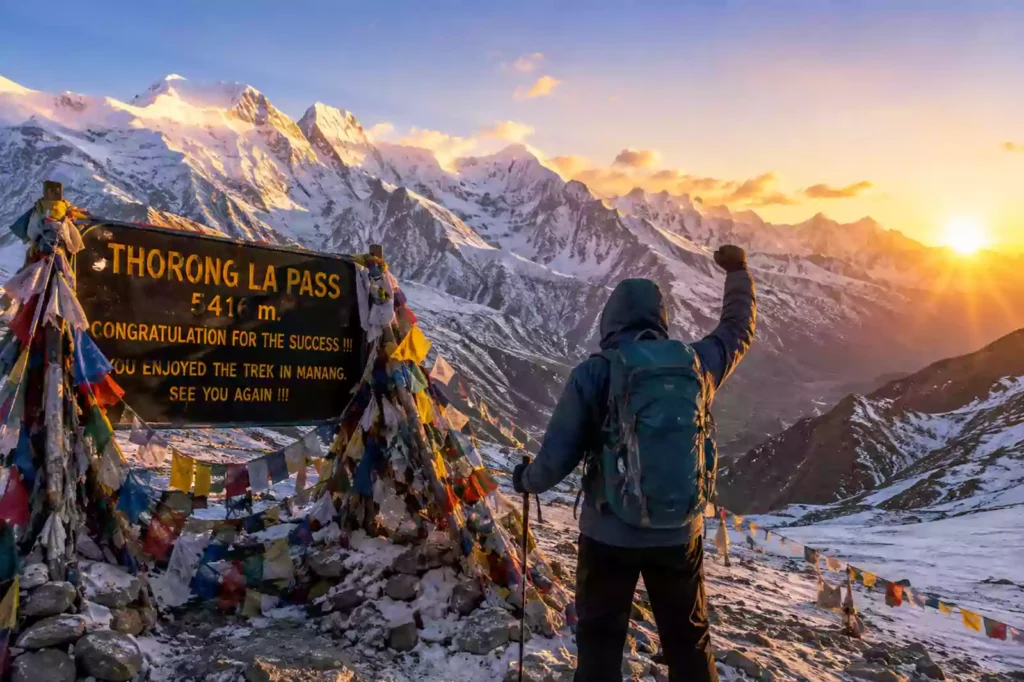 Thorong La Pass crossing guide tips — trekker at Thorong La Pass summit sign 5416m with Annapurna range at sunrise, Nepal | Nepal Footprint Holiday