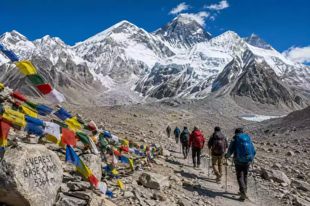 Trekkers walking along the Everest Base Camp trail decorated with colorful Buddhist prayer flags by Nepal Footprint Holiday