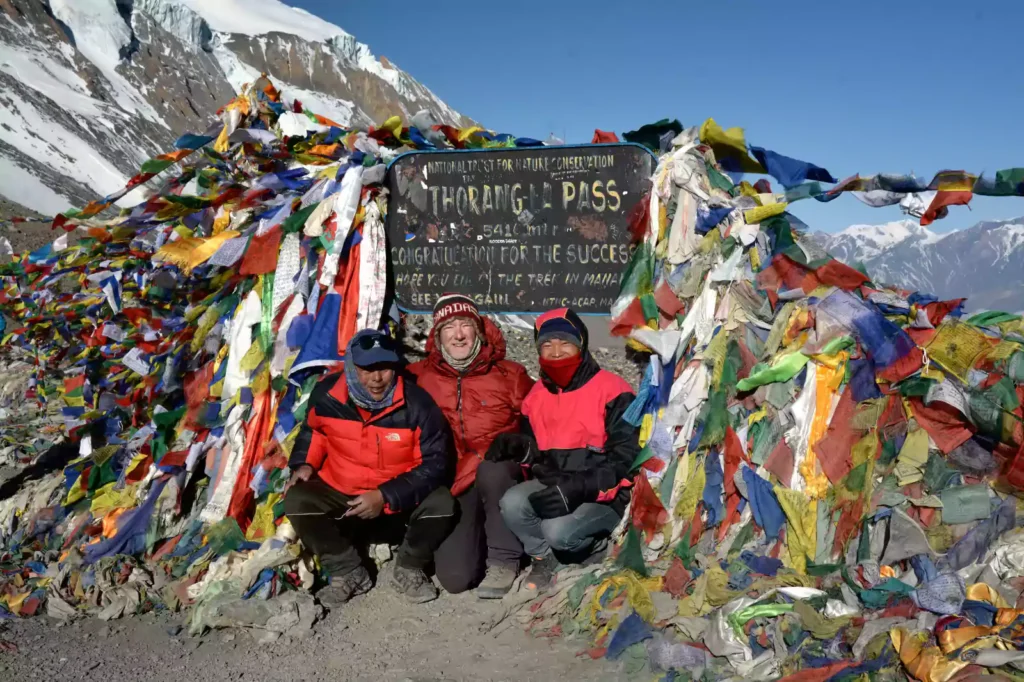 Trekkers posing at Thorong La Pass banner at 5,416m on the Annapurna Circuit Trek with Nepal Footprint Holiday