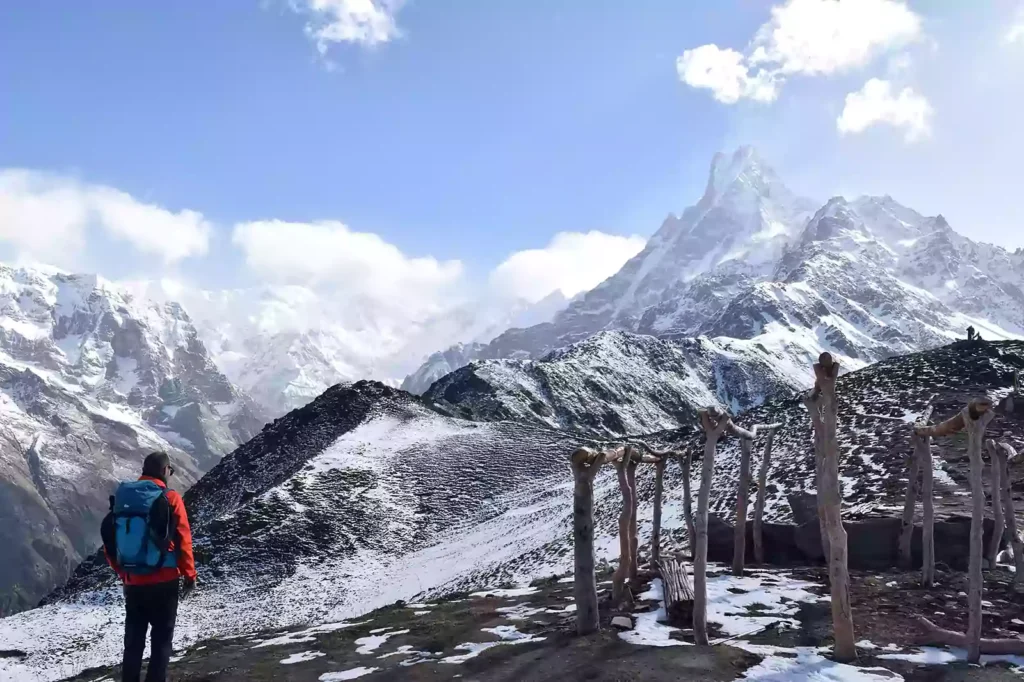 A trekker with a licensed guide walking along the high altitude ridge of the Mardi Himal trail.