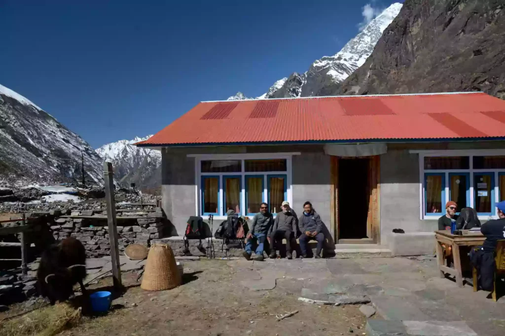Trekker resting outside a traditional Himalayan tea house lodge with flags during a Nepal Footprint Holiday trek
